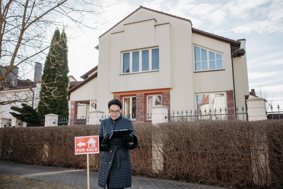 A real estate agent standing outside a house with a 'For Sale' sign